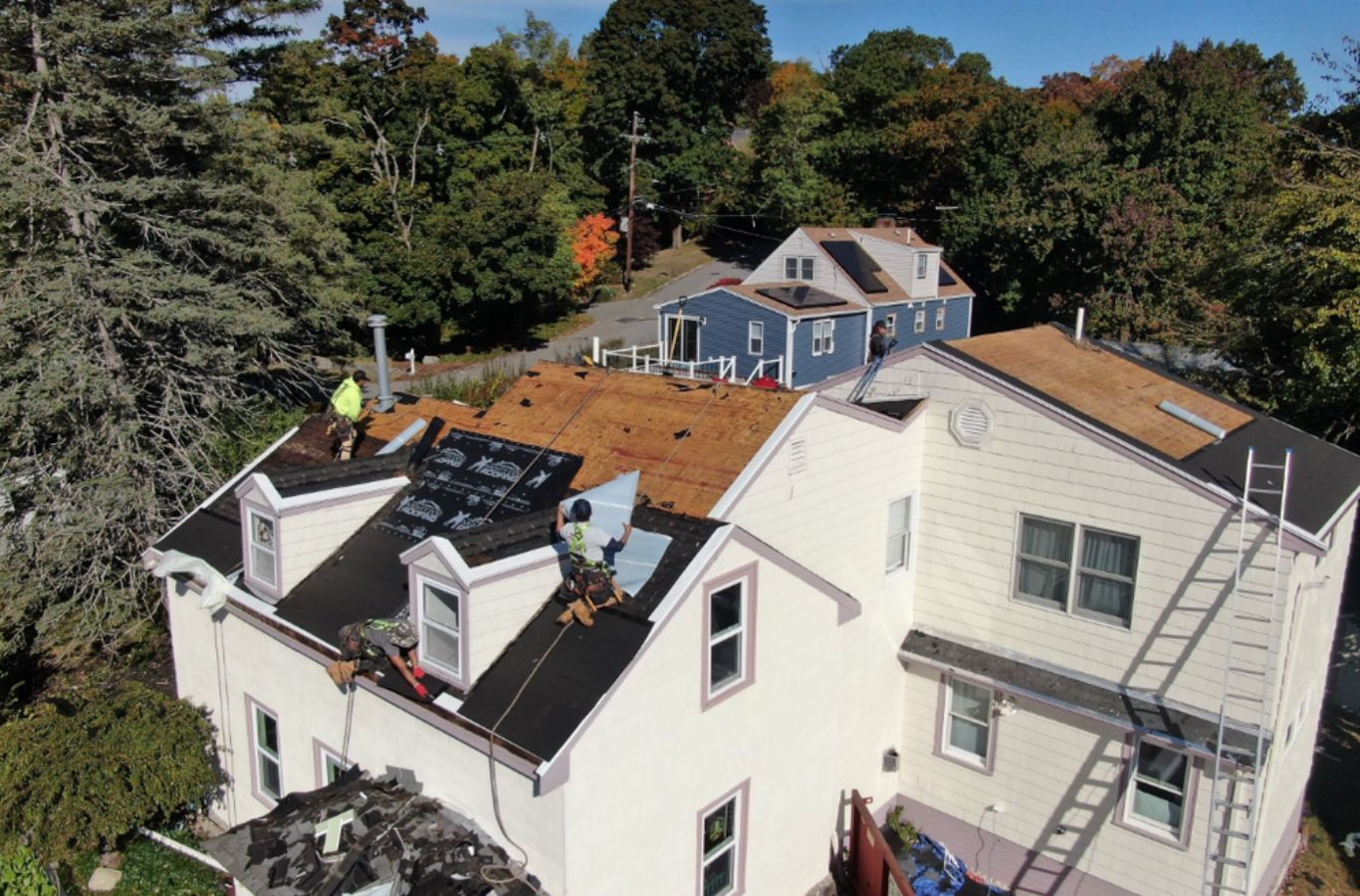 Un miembro del equipo de Mighty Dog Roofing of Greater Middlesex County reparando tejas en Westford, MA, destacando la precisión y profesionalidad.